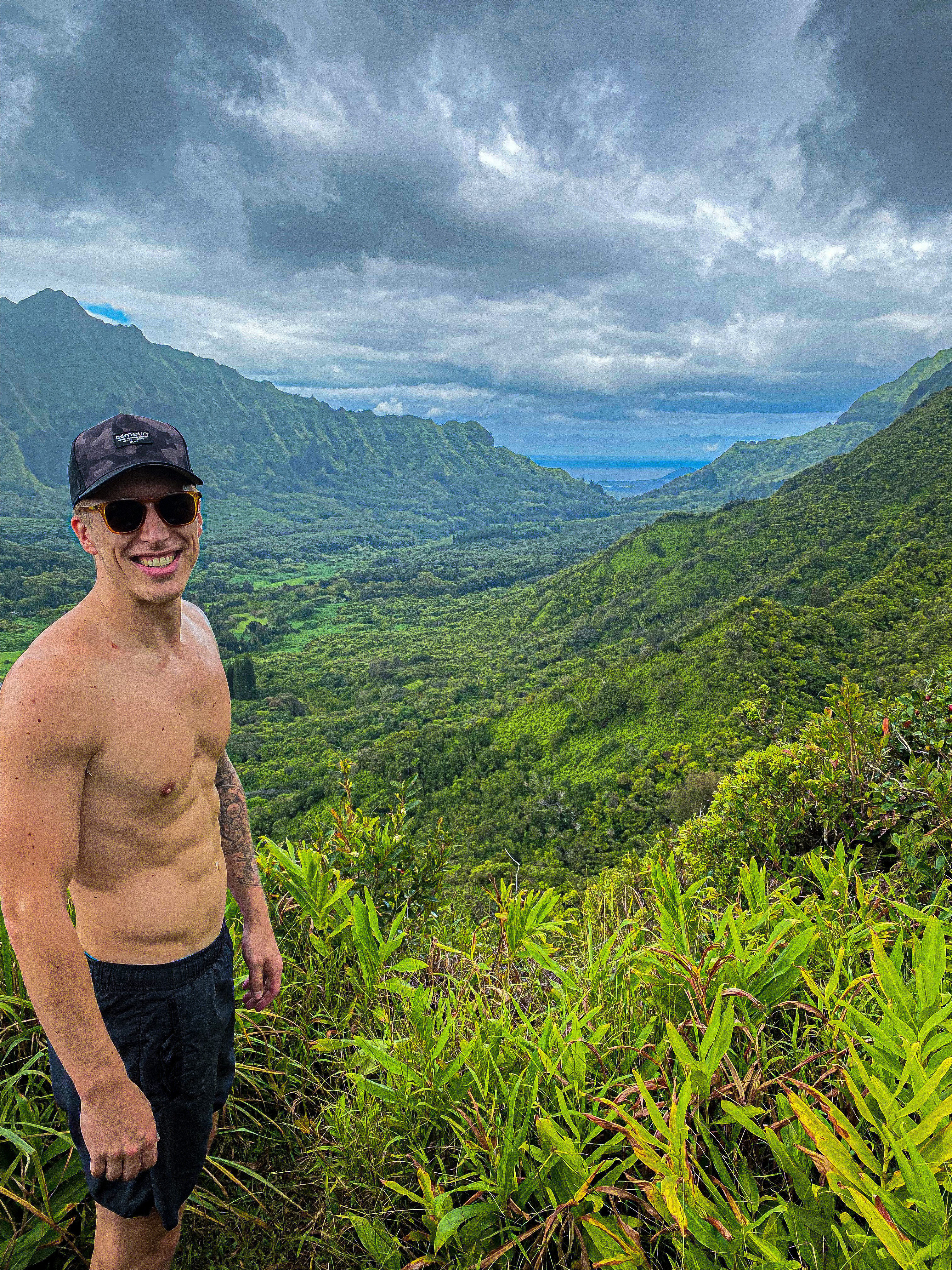 Shirtless guy with tropical mountains in the background.